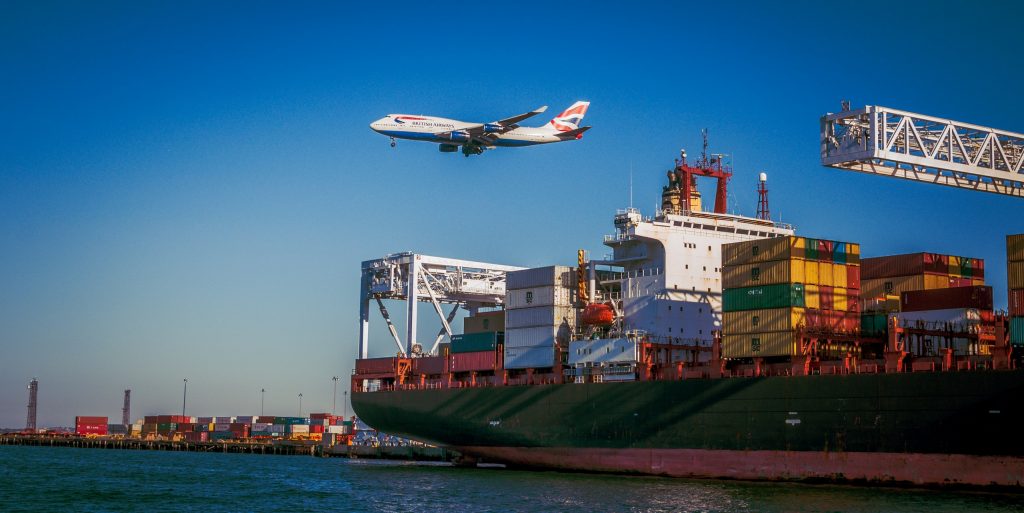 British Airlines Plane flying over Cargo Ship at Port