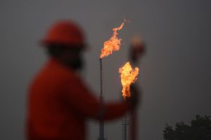A worker takes measurements in front of gas flares at the state energy company Petroleos Mexicanos (Pemex) Perdiz Plant, which is unable to process the vast volumes of gas sent from the Ixachi field, outside of Tierra Blanca, Mexico May 4, 2022.